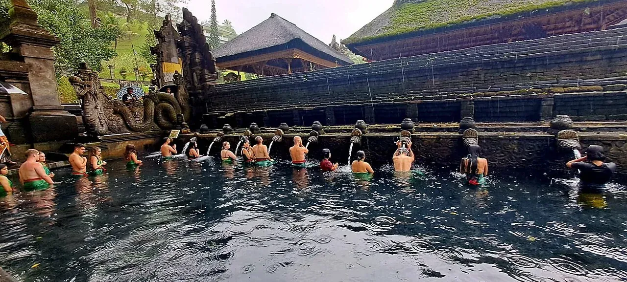 Visitors beside the water spouts and bathing pool at Tirta Empul