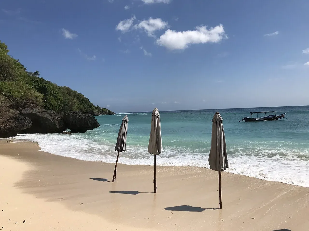 The sandy cove at Padang Padang with parasols and a rock wall