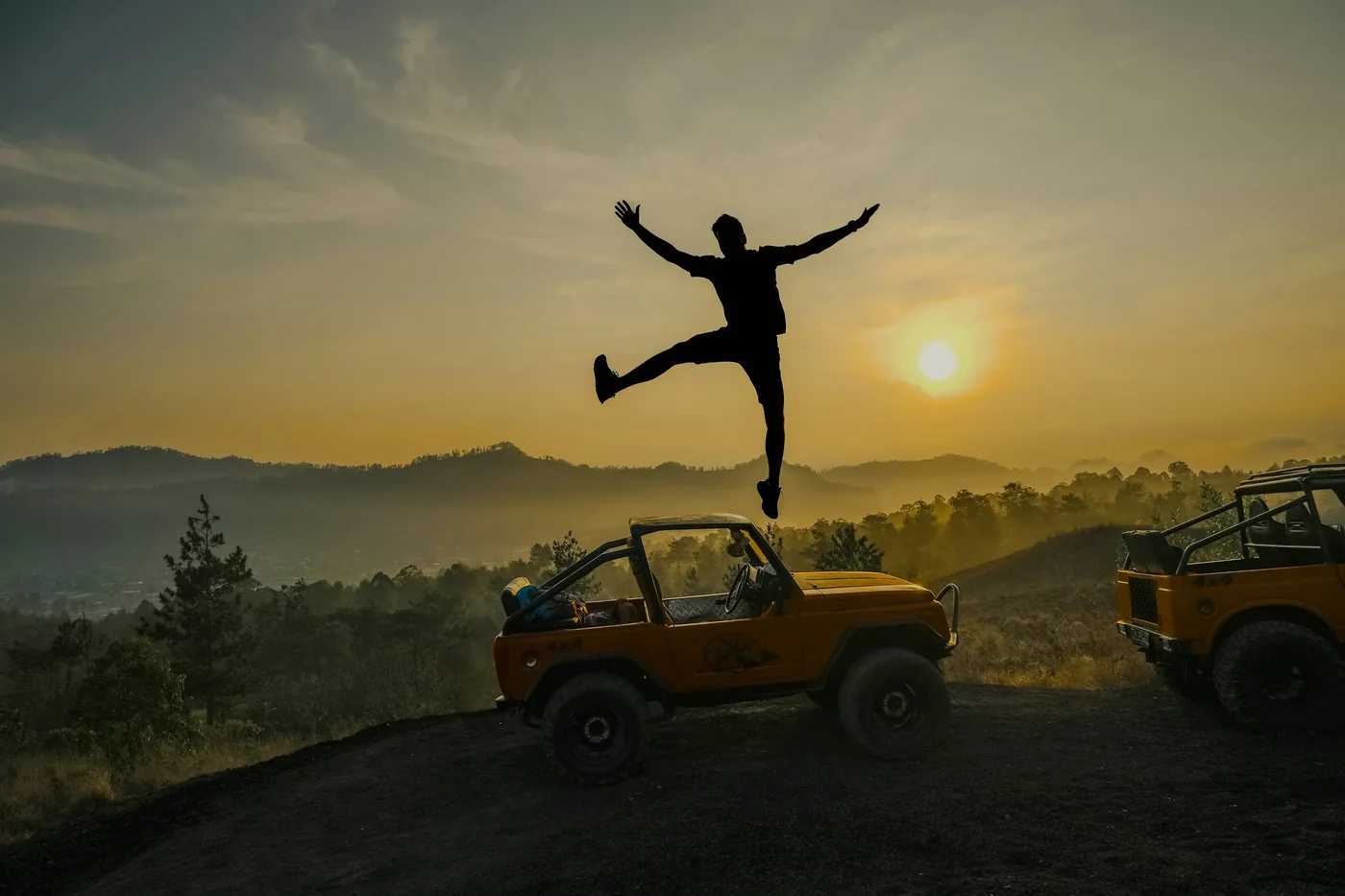A silhouette above a jeep at Mount Batur in the early morning light — A jeep in the Batur area · illustrative photo