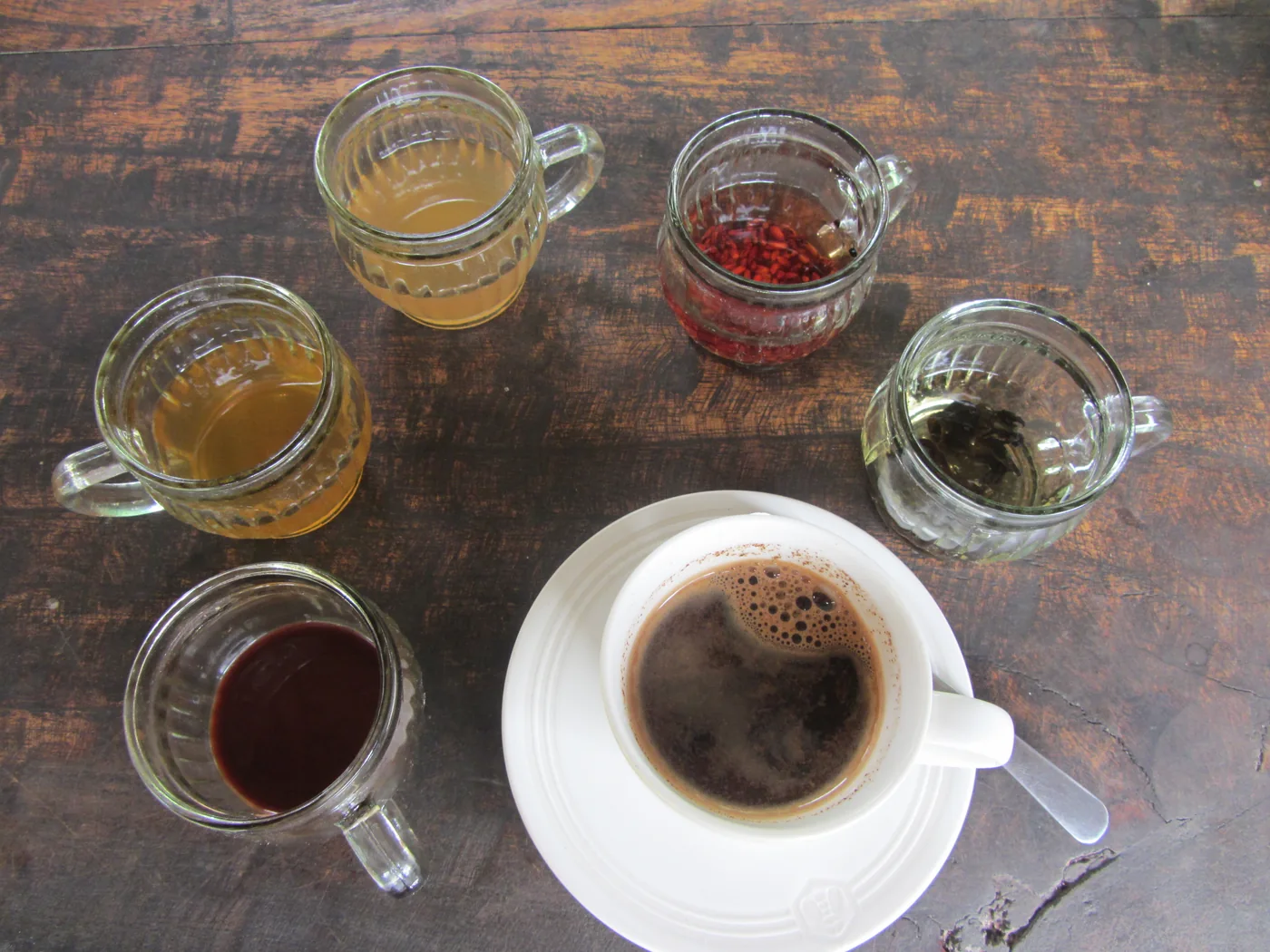 A cup of coffee and several tasting drinks on a wooden table in Bali — Coffee tasting in Bali · illustrative photo